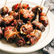 Bacon wrapped dates on a plate with toothpicks in the dates