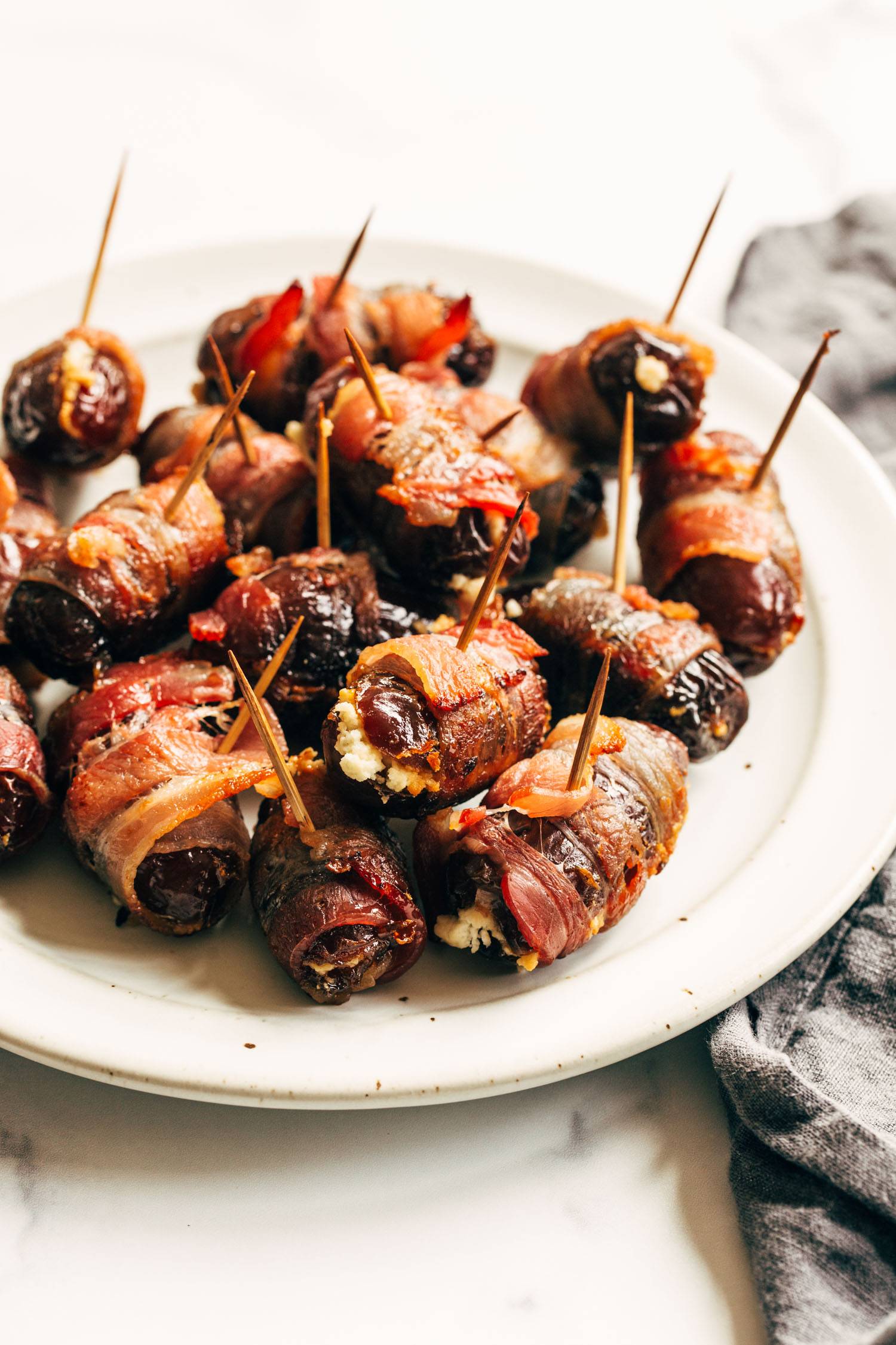 Bacon wrapped dates on a plate with toothpicks in the dates