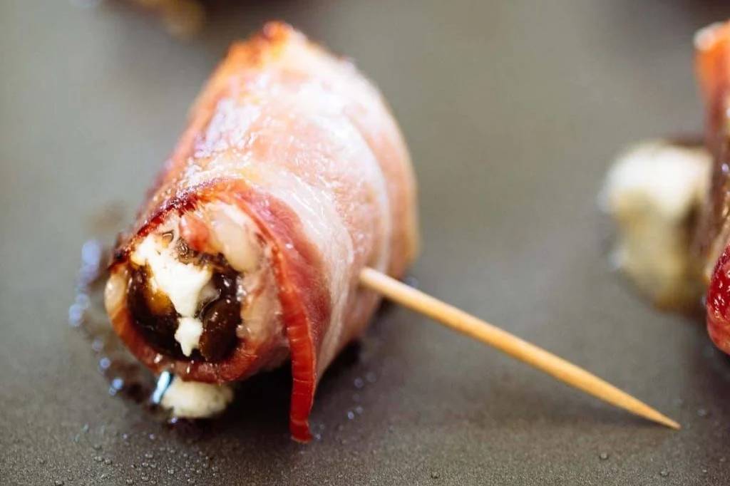 Bacon wrapped date on a sheet pan.