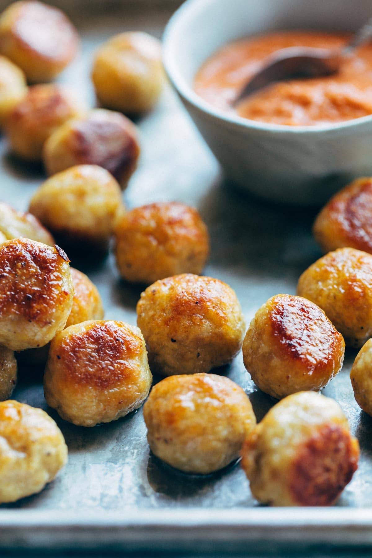 Baked Chicken Meatballs on a sheet pan with sauce.