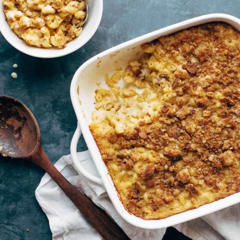 Baked mac and cheese in a pan with a wooden spoon.
