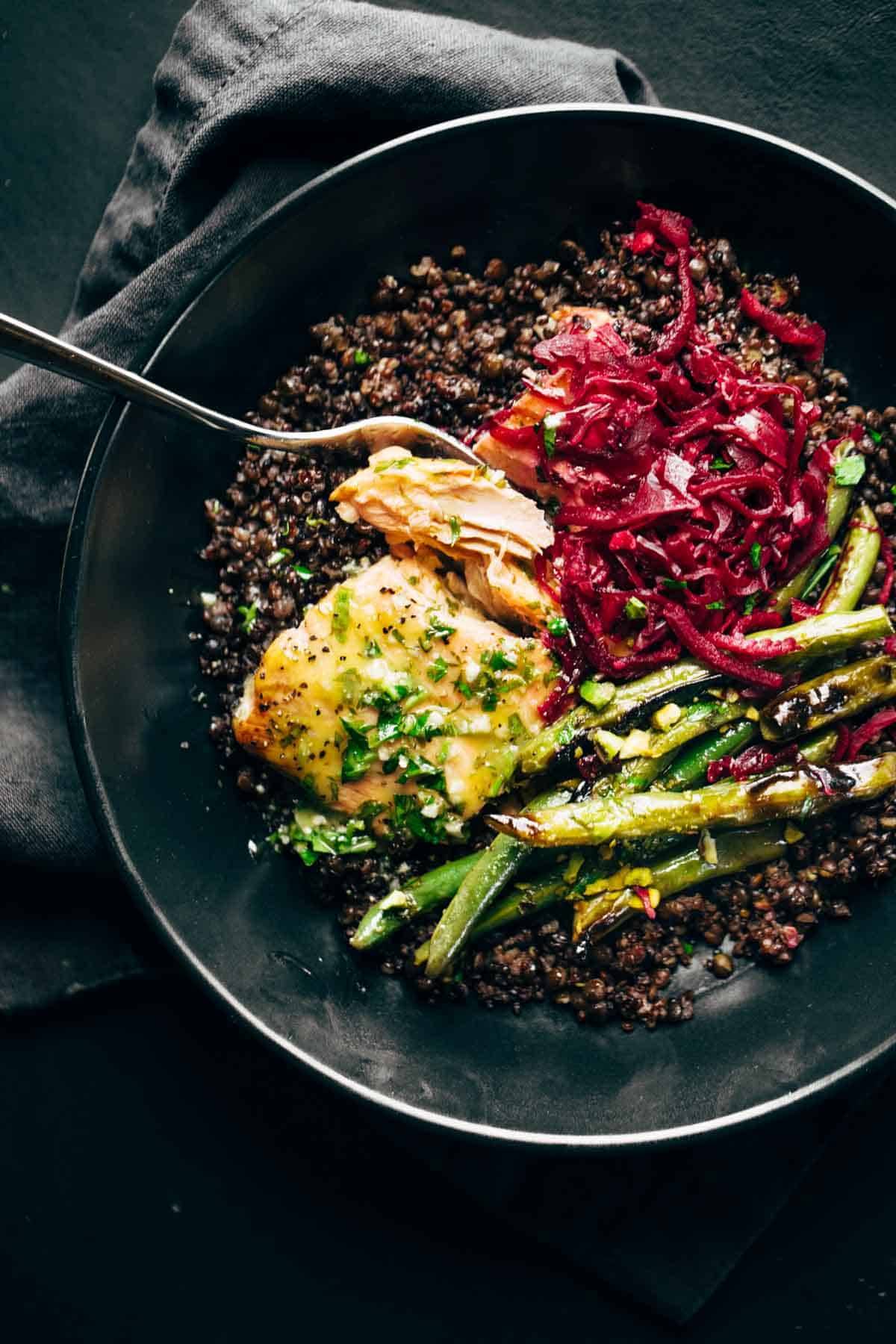 Baked salmon with lentils, green beans, and sauerkraut in bowl.