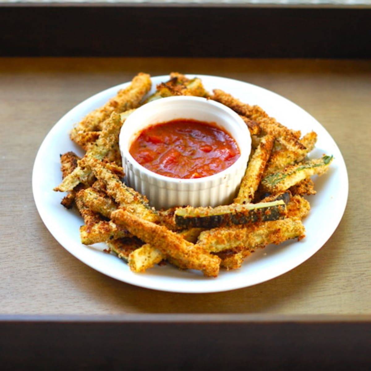 Baked Zucchini Fries with sauce on a plate.