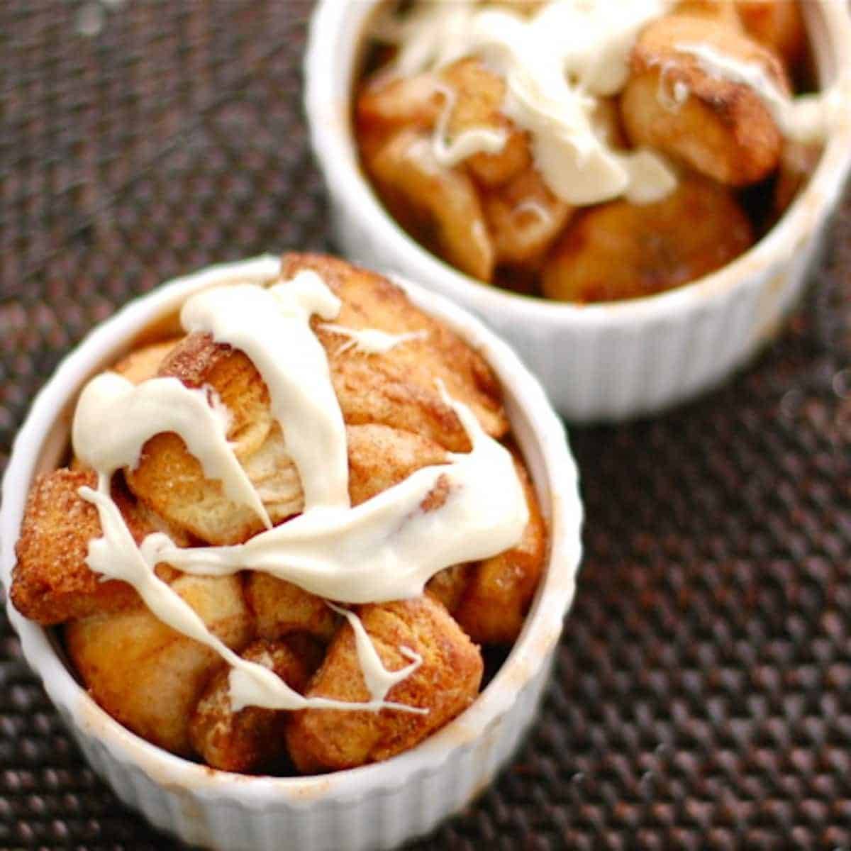 Banana monkey bread in small white dishes with frosting drizzle.