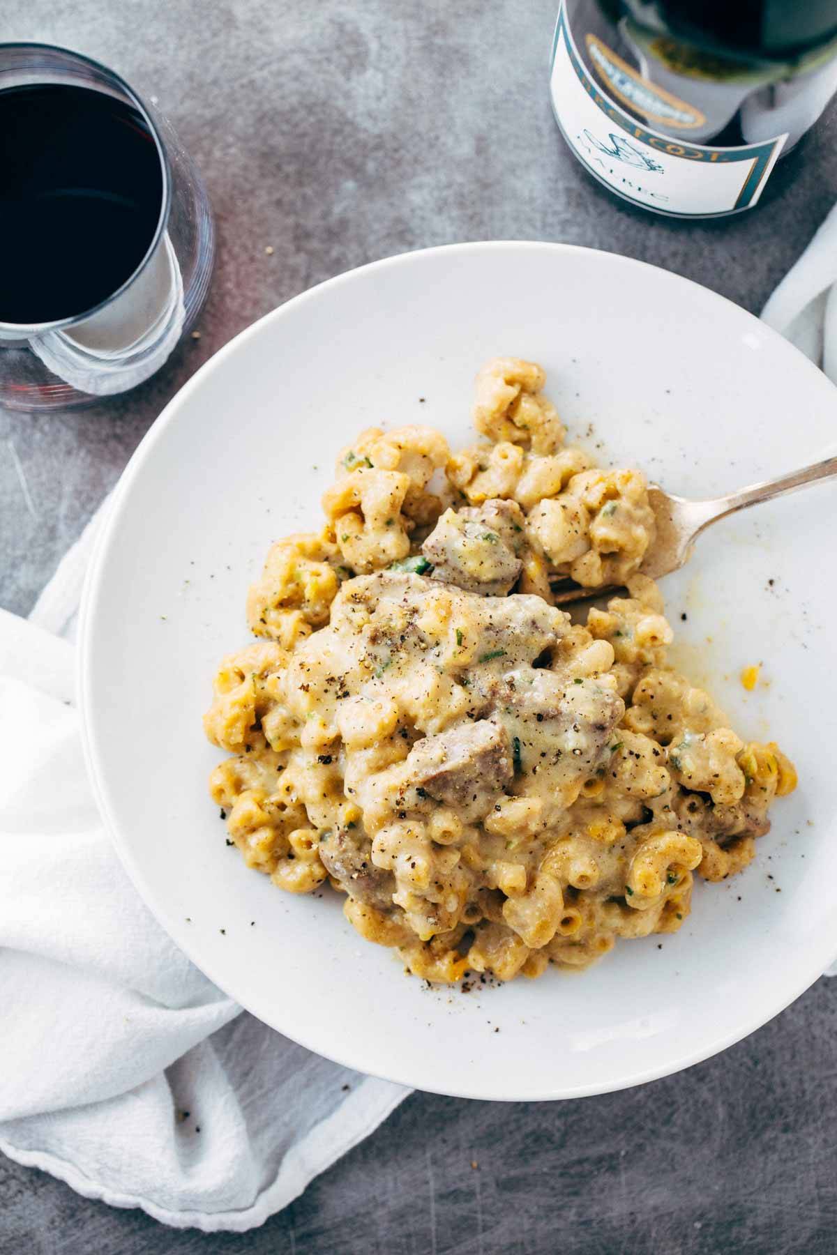 Steak and Cheddar Mac and Cheese on a white plate with a fork.