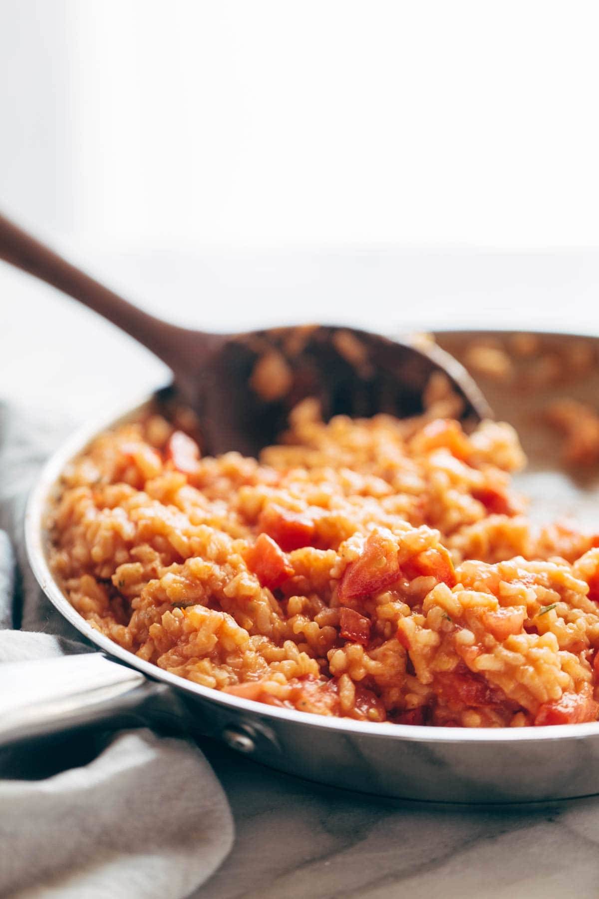 Creamy Tomato Risotto with Pan Fried Barramundi with a wooden spoon
