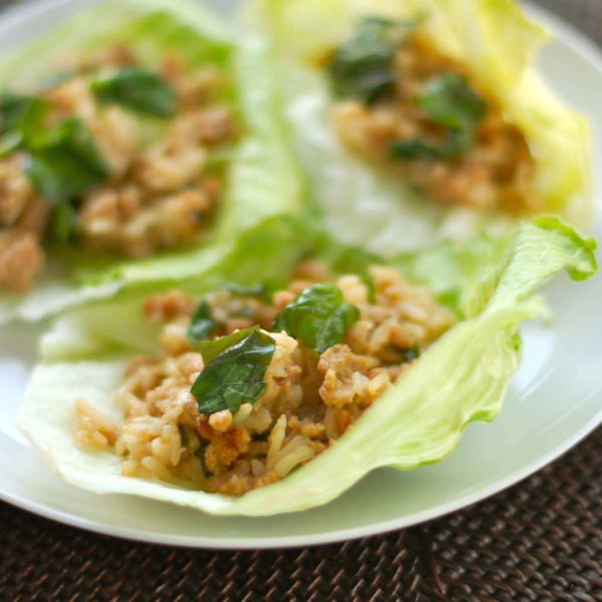 Basil chicken lettuce wraps on a white plate.