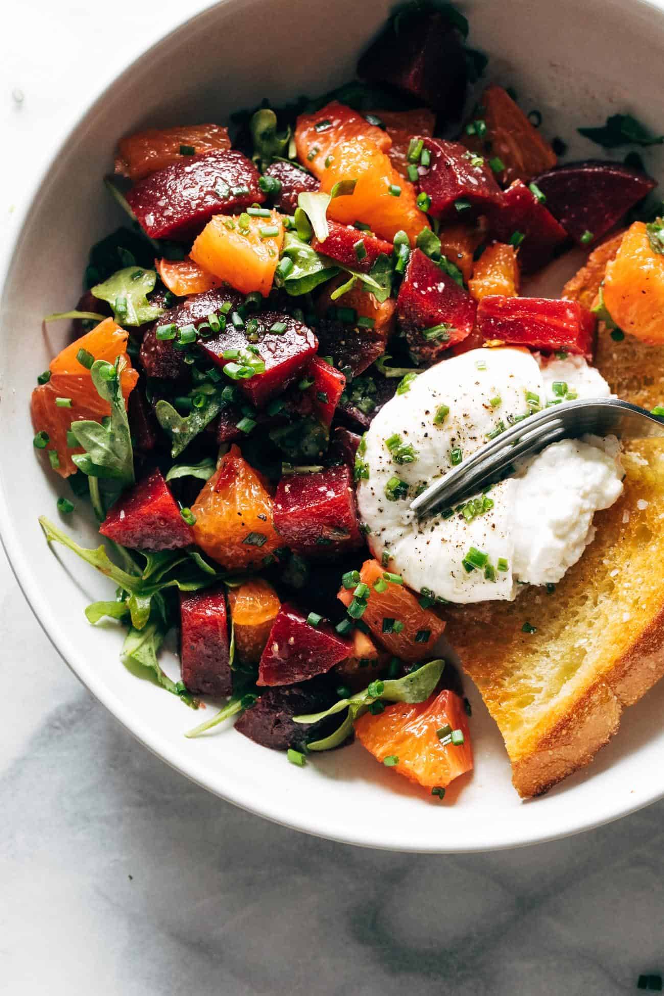 Beet and burrata salad in a bowl with fried bread and a fork