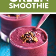 Berry green smoothie in a glass with granola on top.