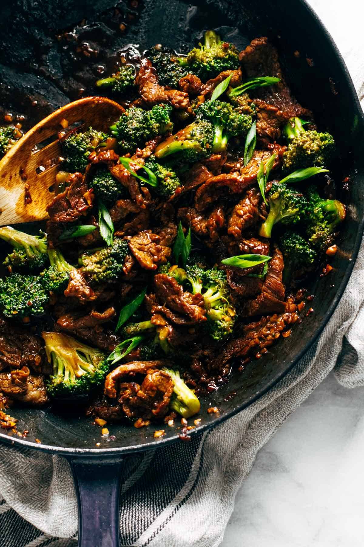 Beef and broccoli in a pan with a spoon.