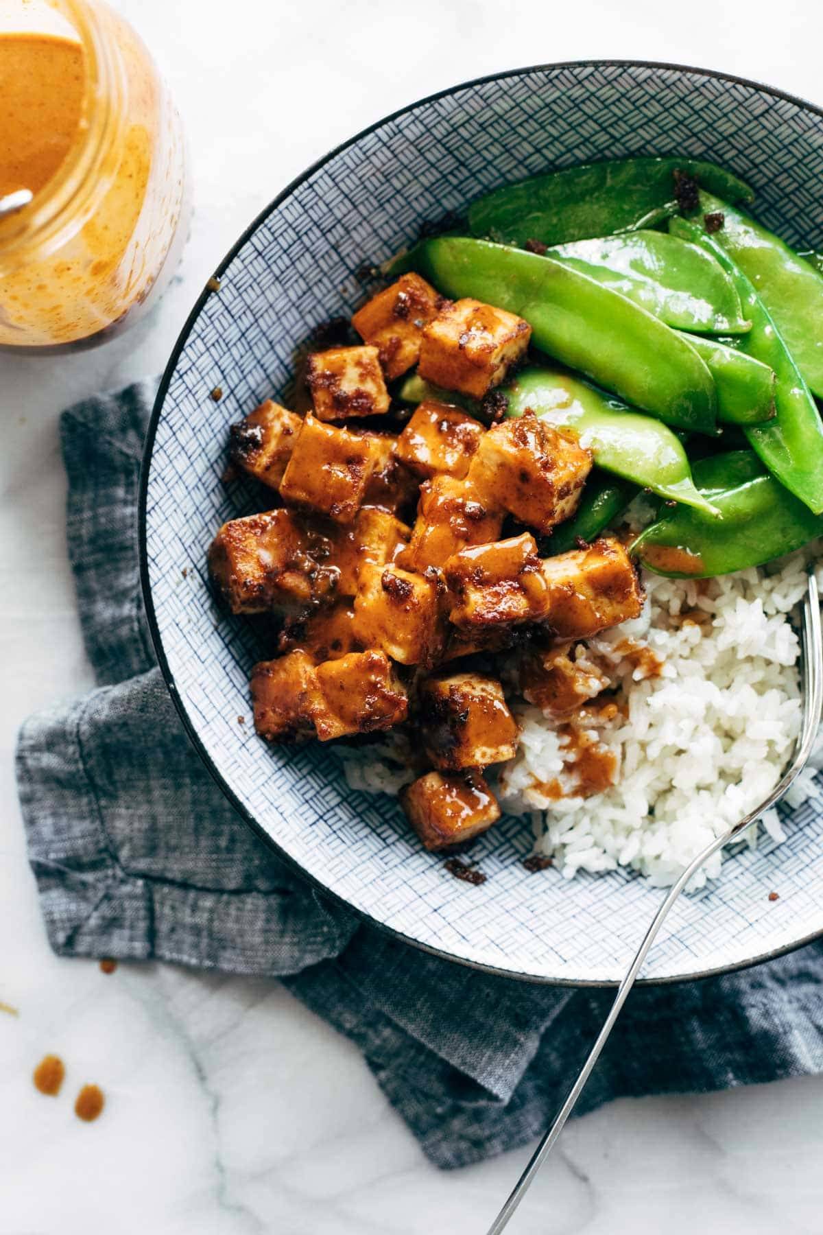 Peanut sauce on tofu with rice and veggies.