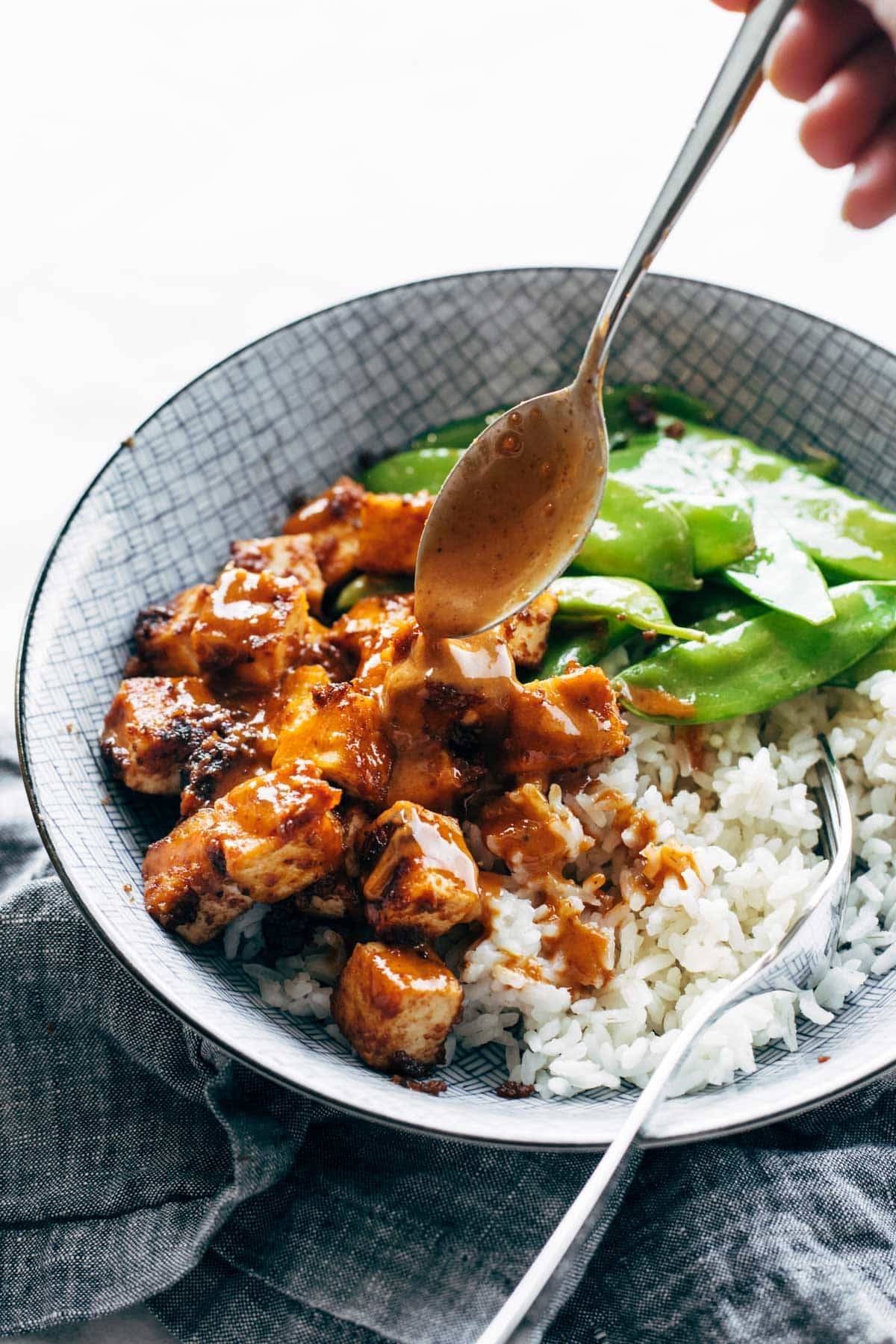 Drizzling peanut sauce on rice bowl.