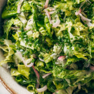 Salad with lettuce, fresh herbs, and pickled onions in a bowl.