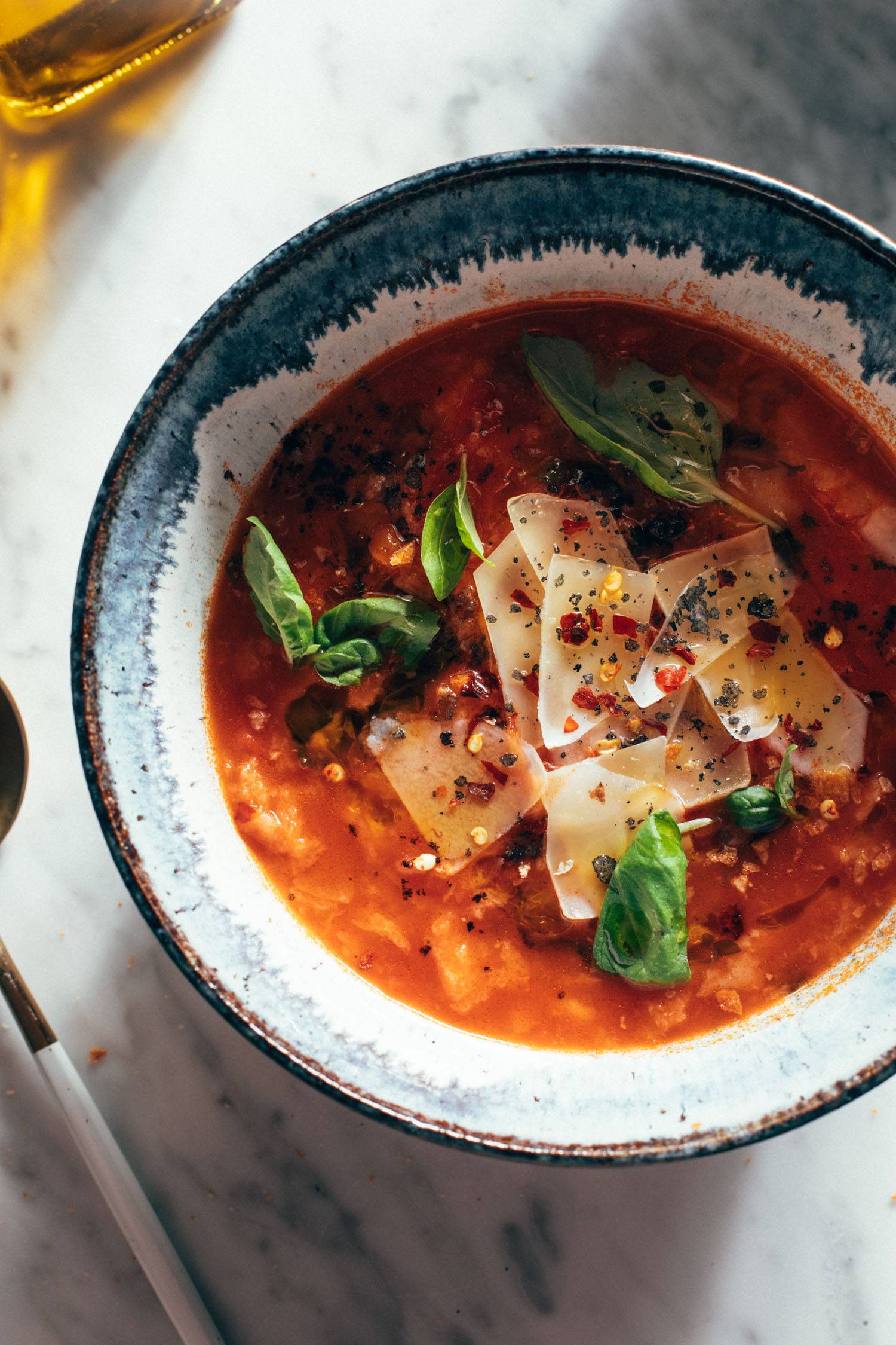 Tomato and bread soup in a bowl with fresh basil and parmesan 