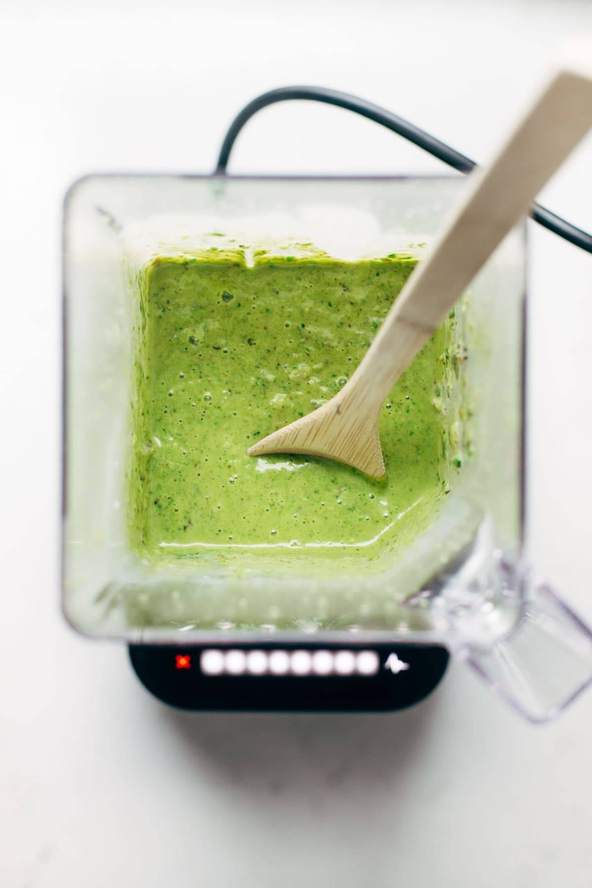 blender of spinach and roasted poblano sauce with wooden spoon
