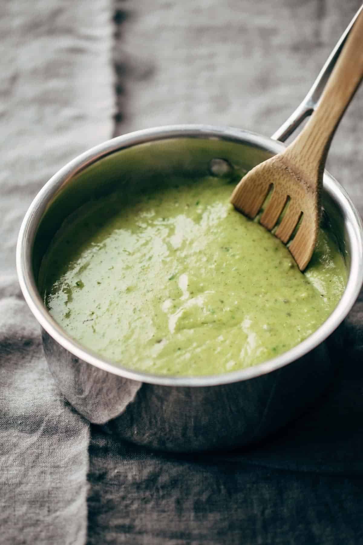 creamy spinach and roasted poblano sauce in a pan with a wooden spoon