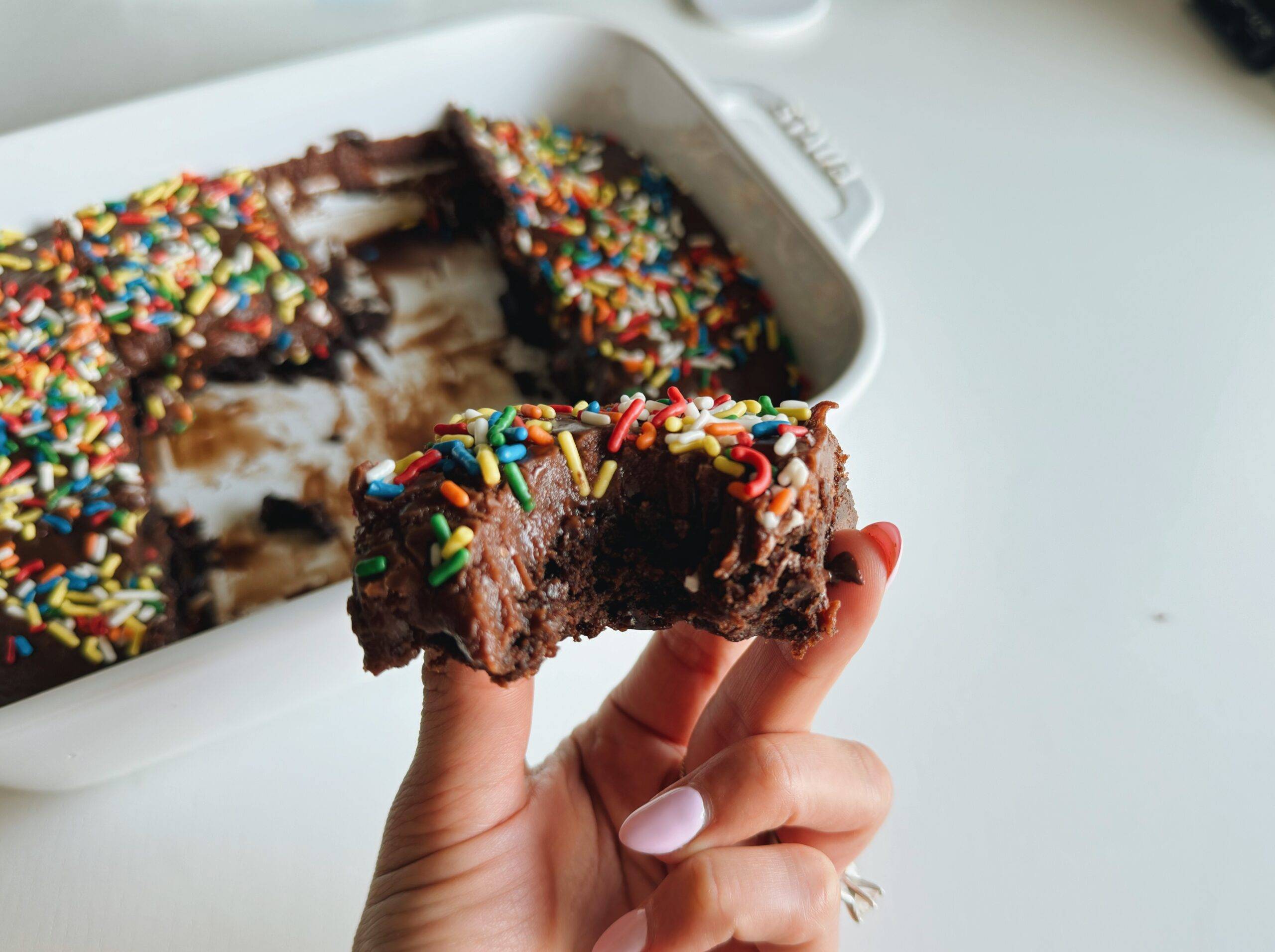 Hand holding a brownie with a bite taken out.