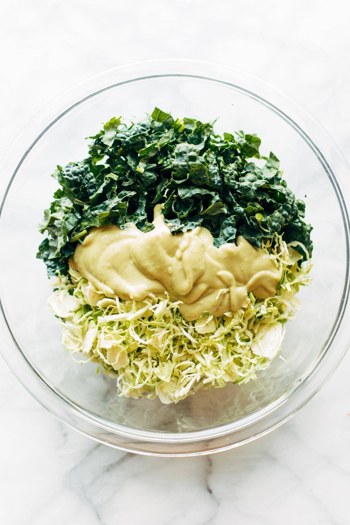 Ingredients for Brussels & Kale Caesar in a bowl.