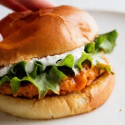 Buffalo chicken burger on a bun with lettuce and whipped feta spread.