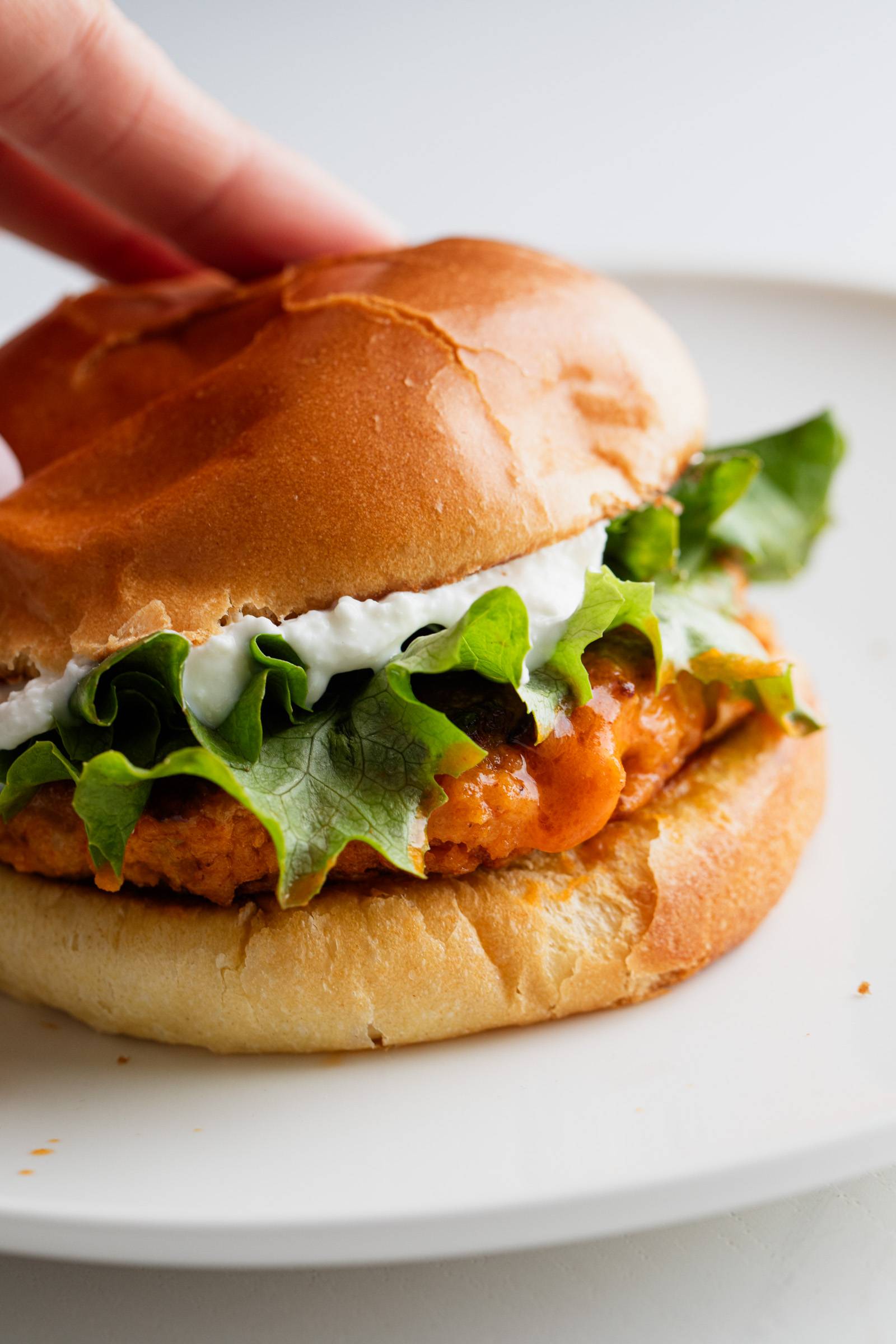 Buffalo Chicken Burger with Feta Spread and Lettuce on a Bun, sitting on a plate