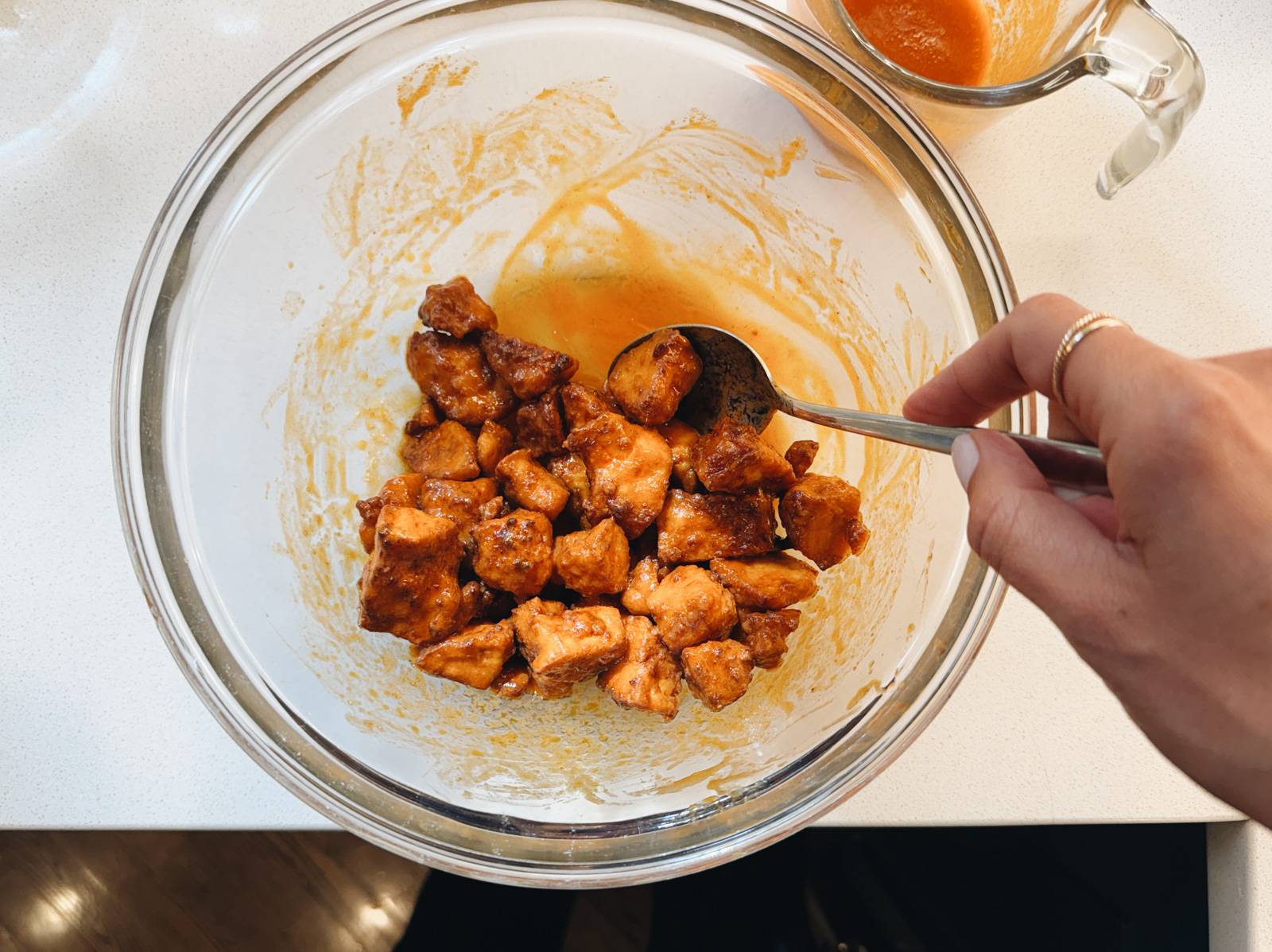 Tossing tofu with buffalo sauce.