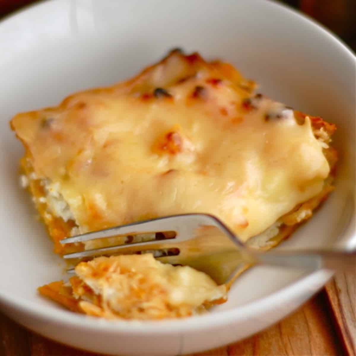 Butternut squash lasagna on a white plate with a fork.