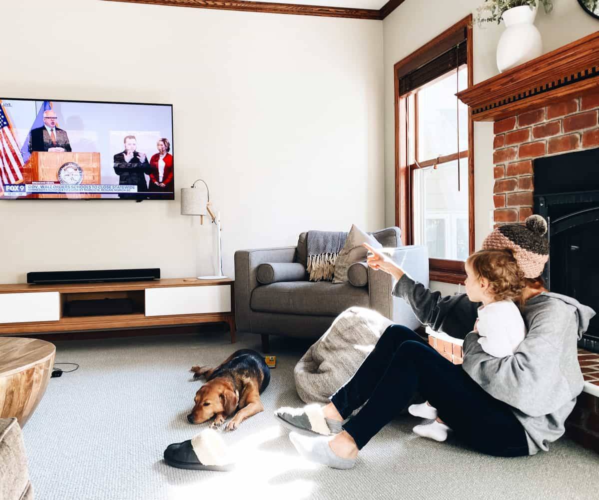 A man and his daughter watching tv in a living room, surrounded by two dogs.