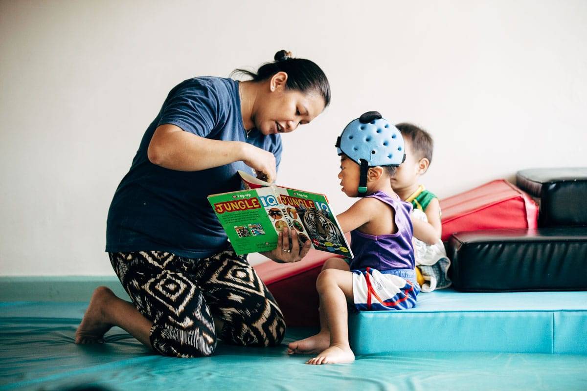 Woman reading a book to two young children.