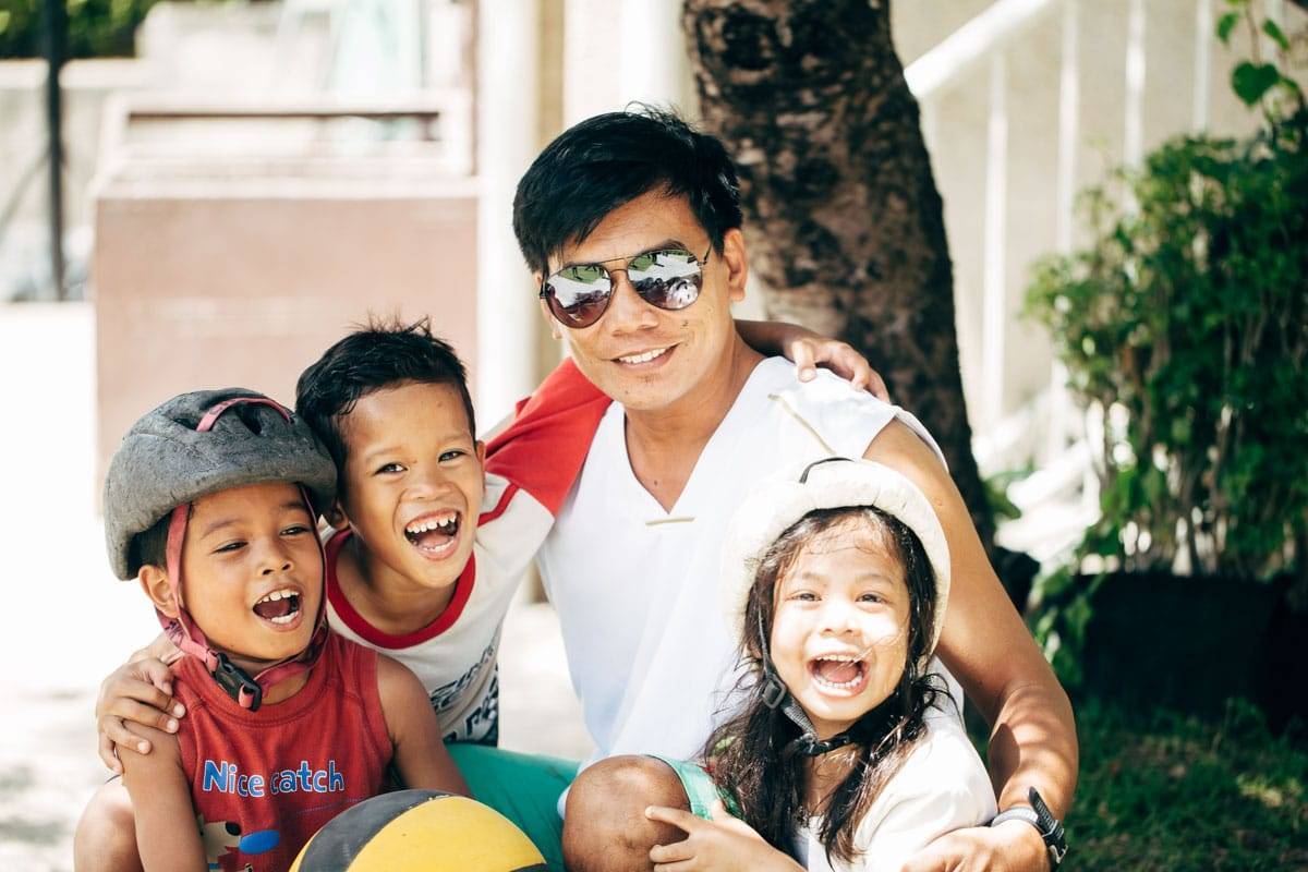 Man smiling with three young children.