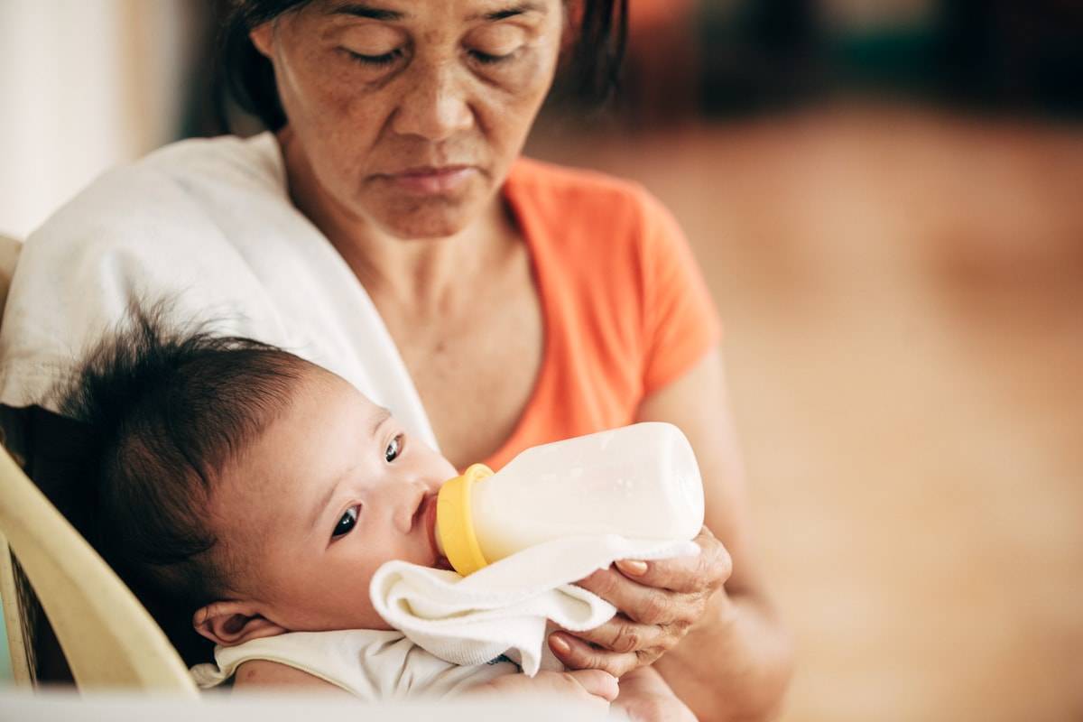 Woman feeding a baby a bottle.