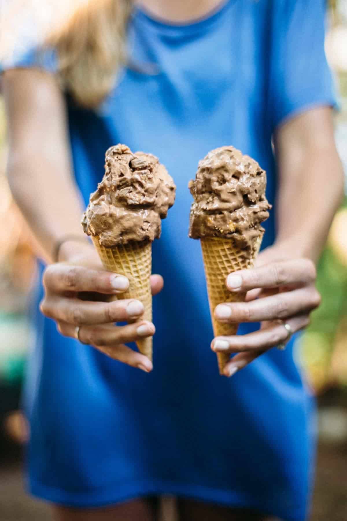 Woman holding two cones of nice cream.