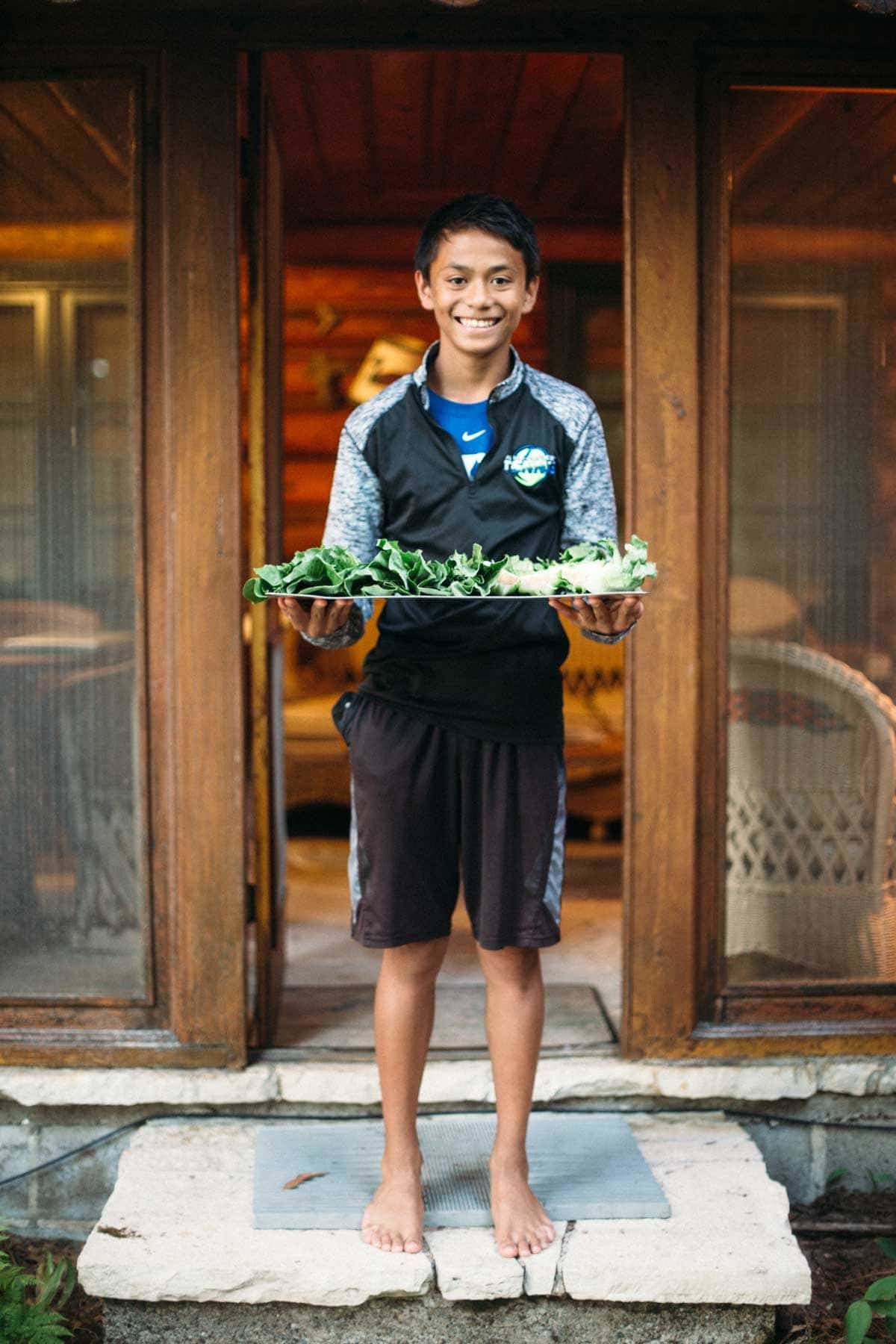 Boy holding a tray of lettuce.