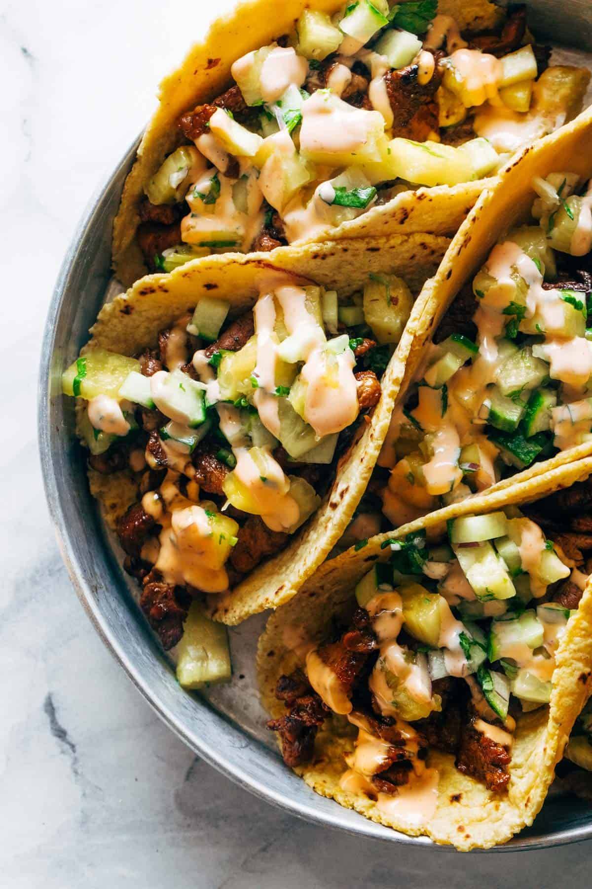 Pork tacos close up photo in a dish with pineapple cucumber salsa