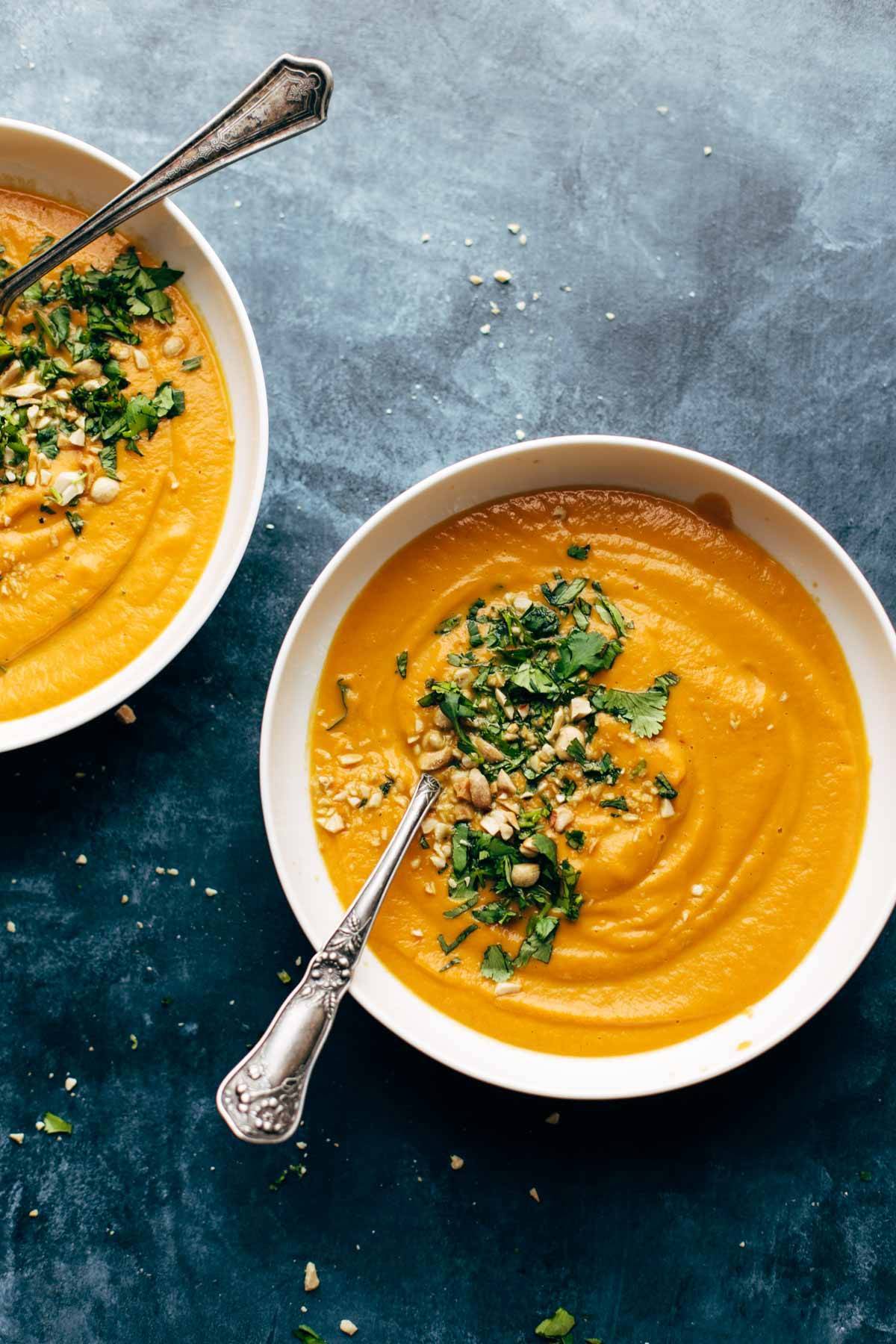 Spicy Vegan Carrot Soup in two bowls with spoons and toppings