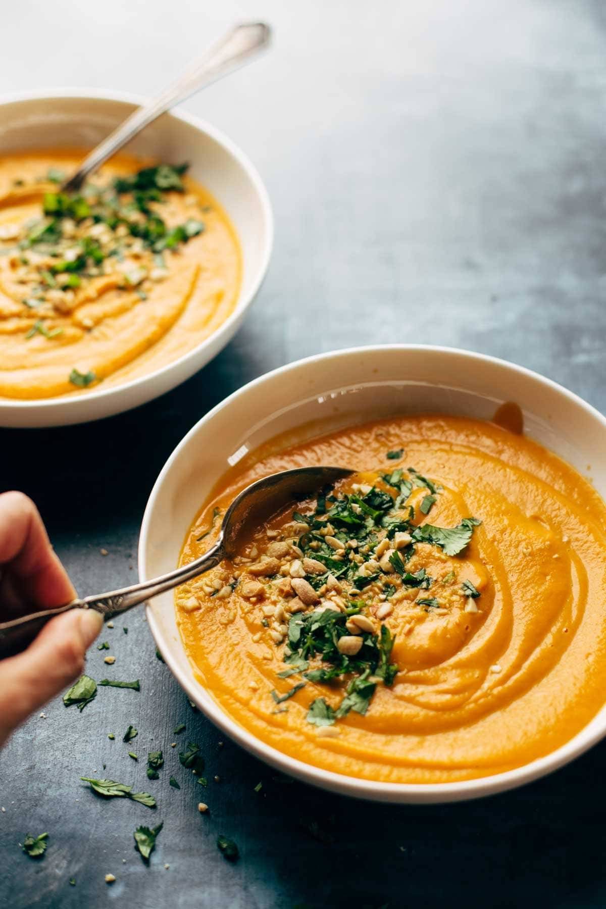 Spicy Vegan Carrot Soup in two bowls with spoons and toppings