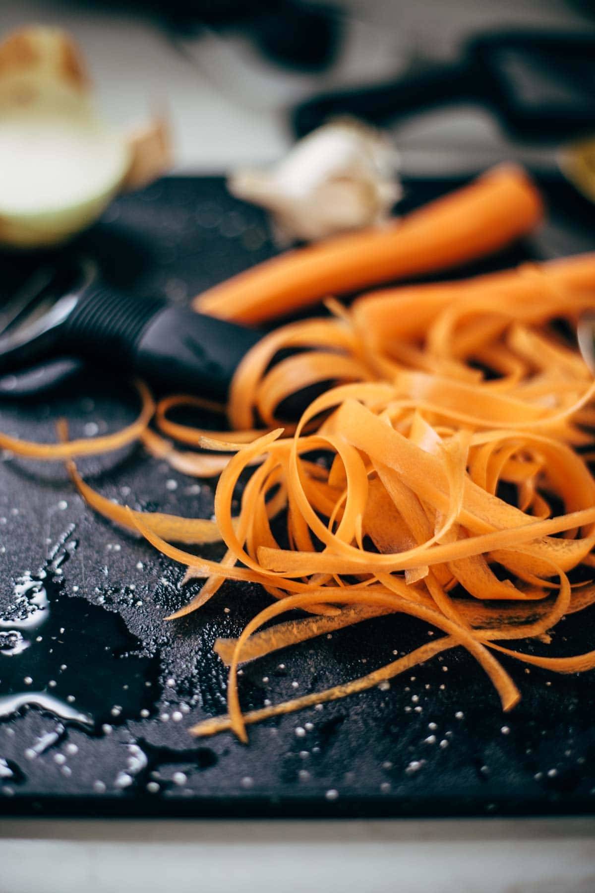 Carrots on a cutting board with a peeler.