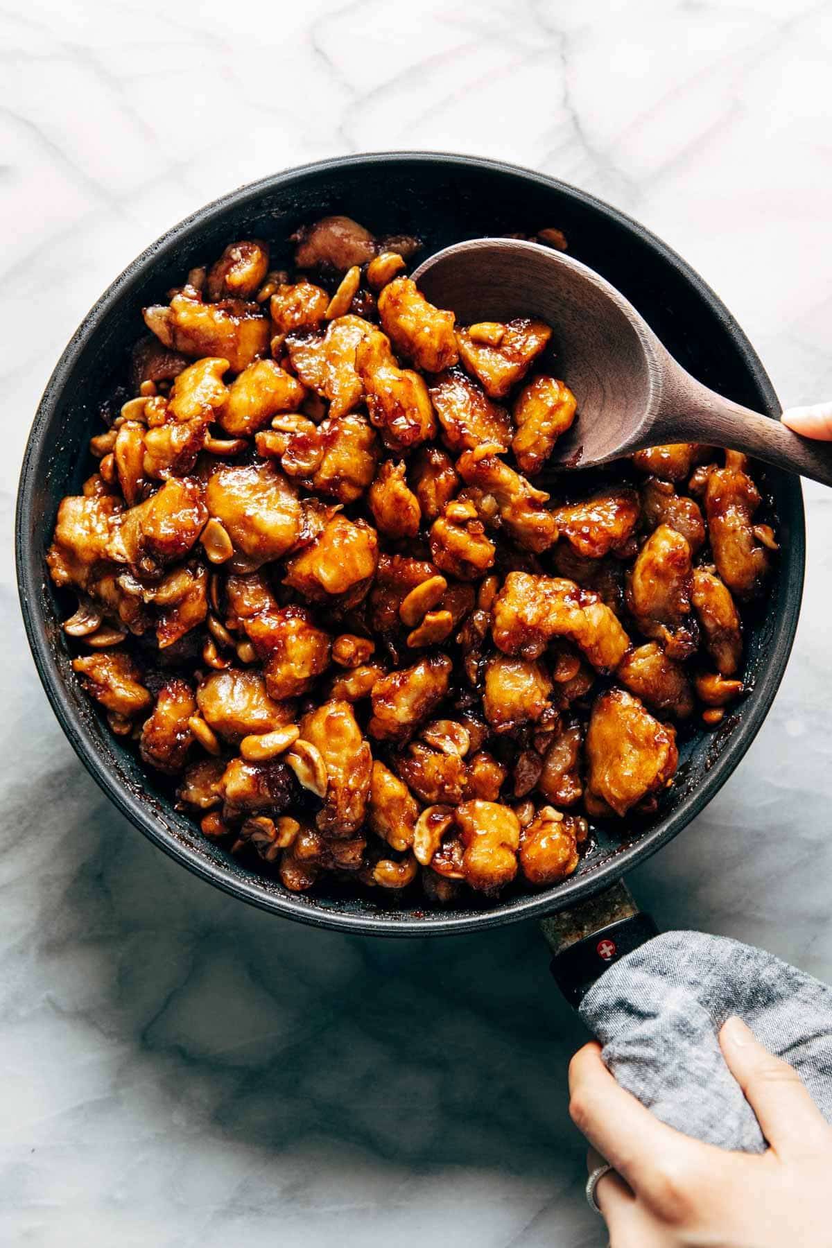 Cashew chicken in a pan with a spoon.