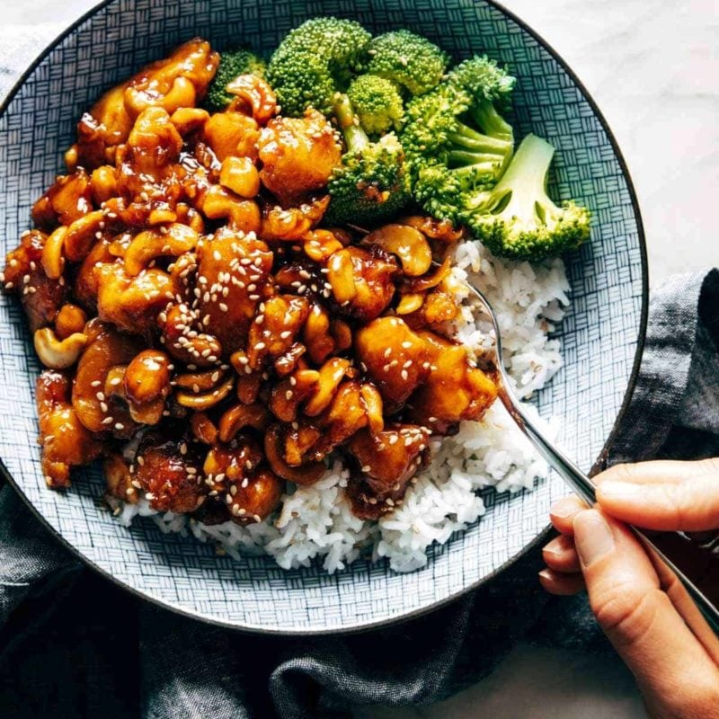 Cashew chicken in a bowl with rice and broccoli.