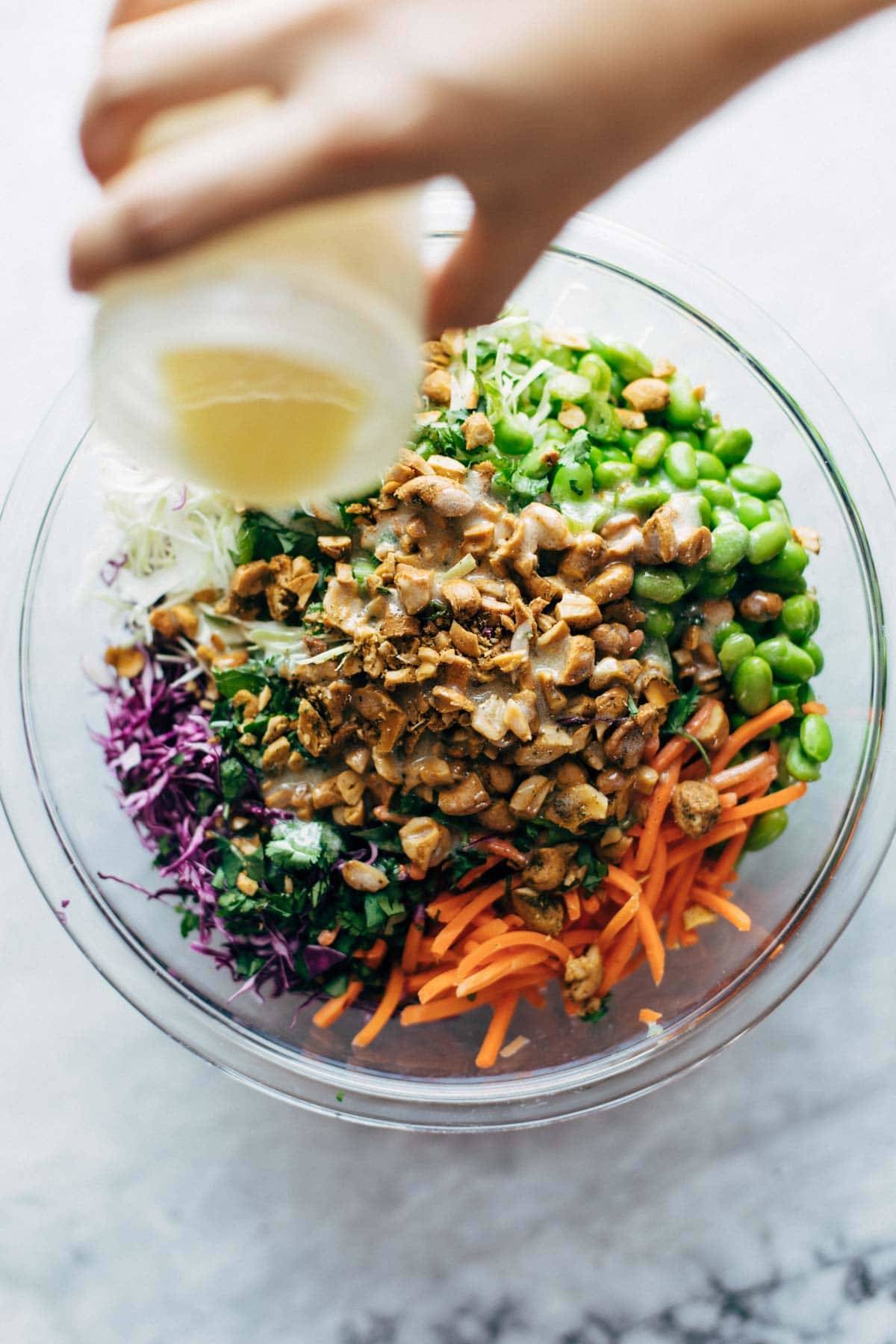 Pouring dressing on Cashew Crunch Salad.