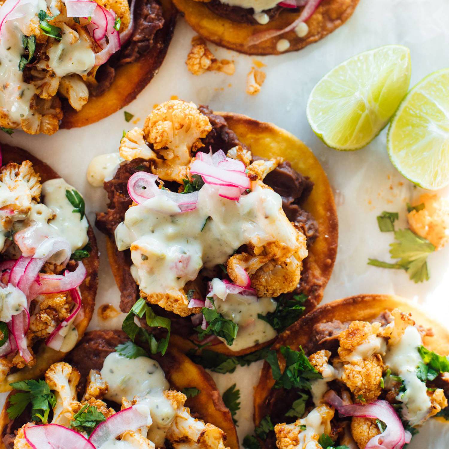 Tostadas topped with black beans, cauliflower, and queso.