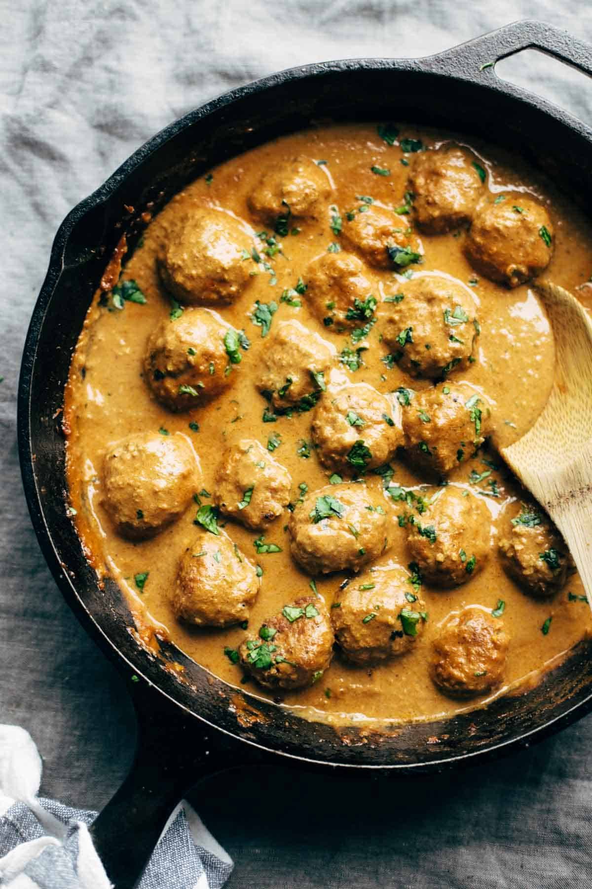 Meatless meatballs in a pan with sauce with wooden spoon.