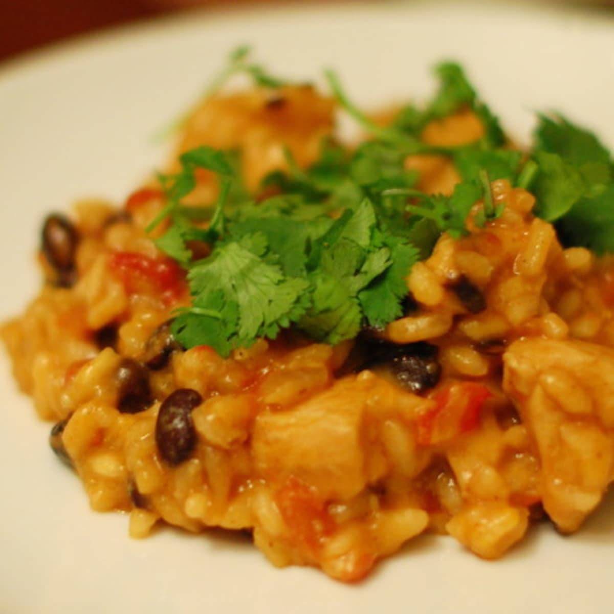 Cheesy black bean risotto with toppings on a white plate.