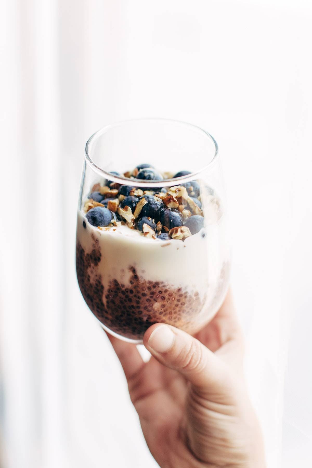 Hand holding Berry Chia Overnight Oats in a glass.