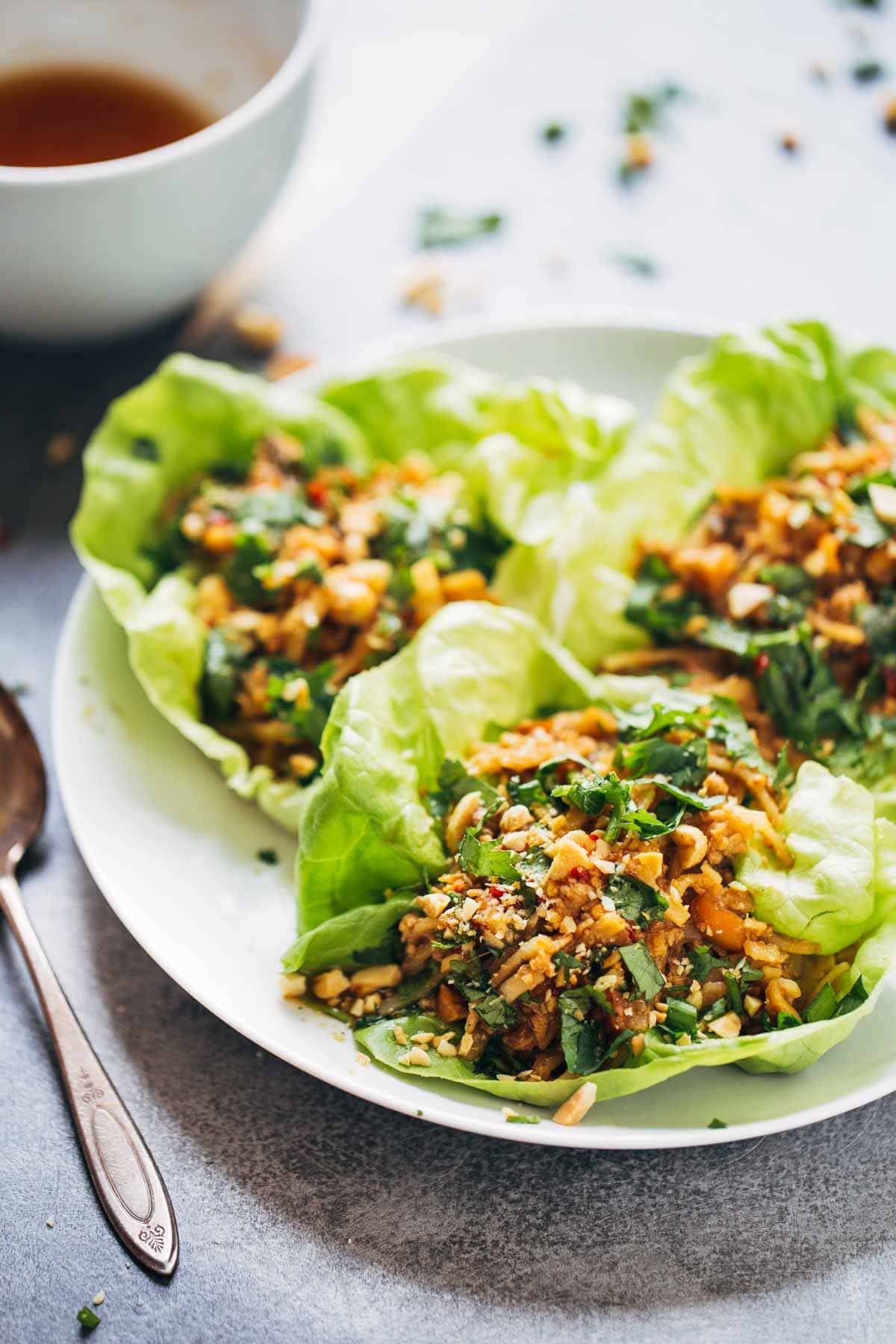 Peanut Chicken Lettuce Wraps with a Ginger Garlic sauce on a white plate.