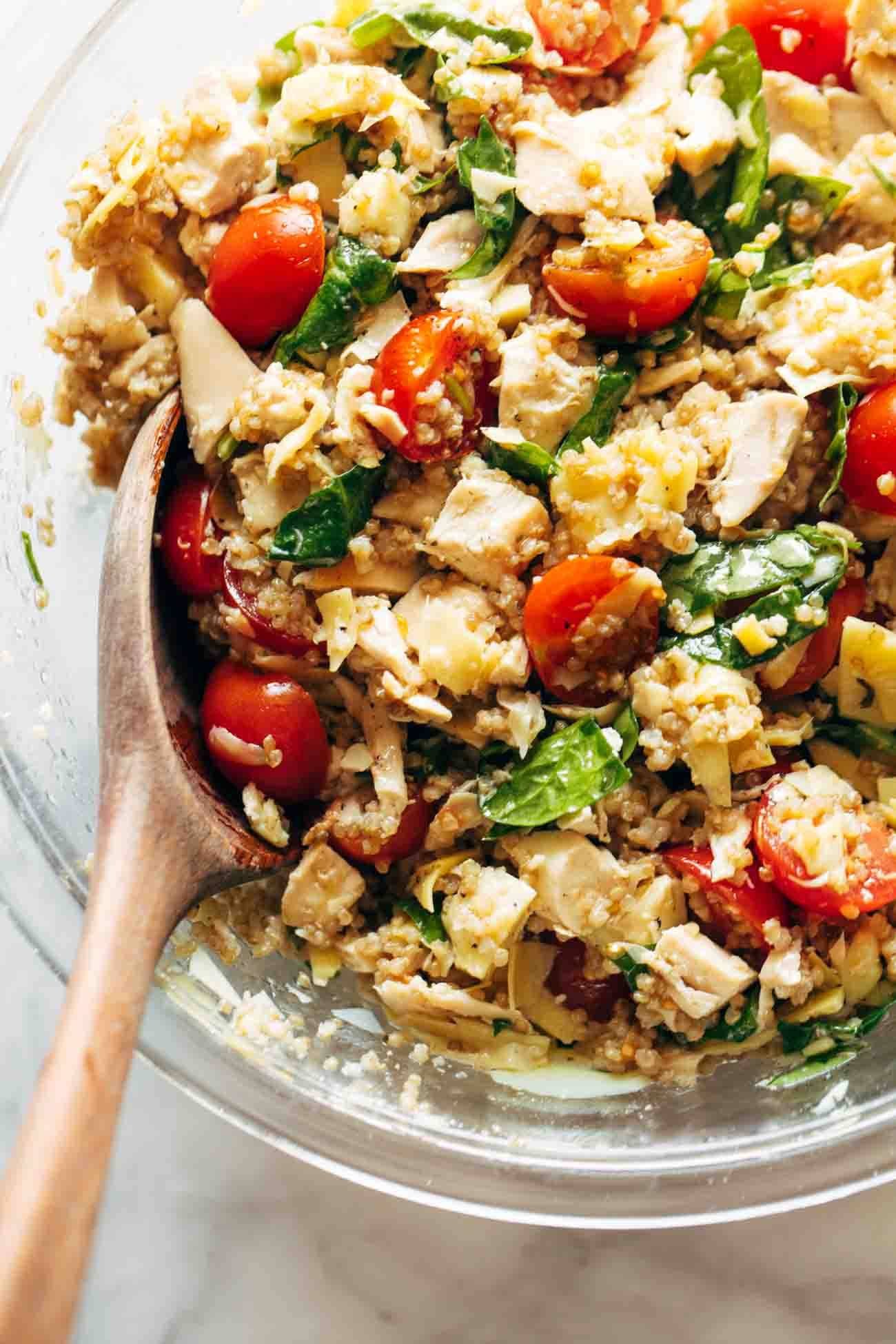 Chicken quinoa salad in a bowl with a wooden spoon