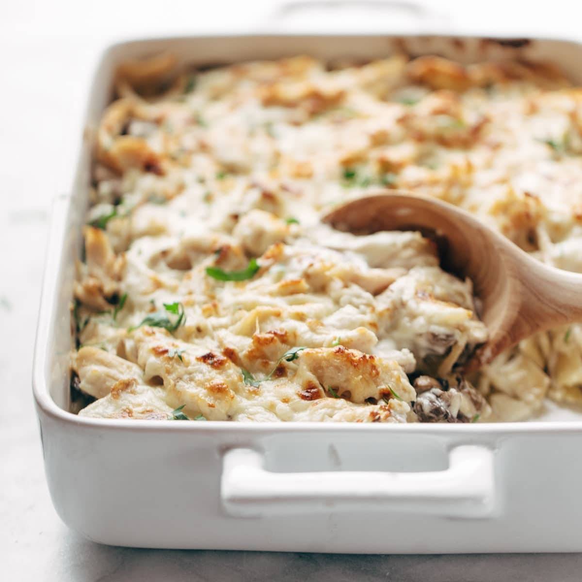 Chicken Tetrazzini baked in a pan with wooden spoon.