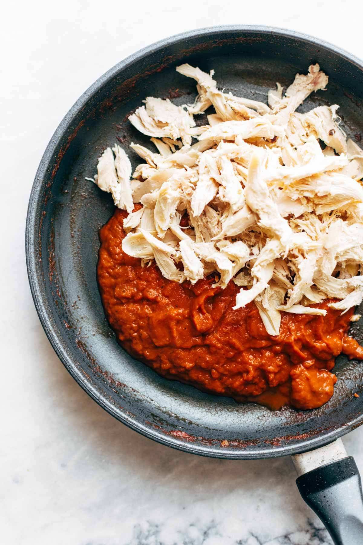 Shredded chicken and tinga sauce in pan.