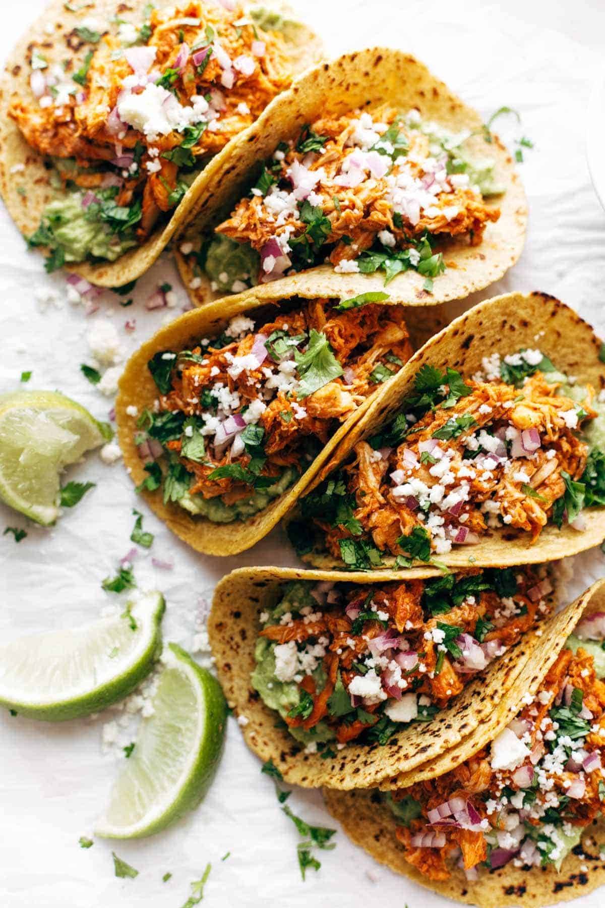 Chicken Tinga Tacos in a row on parchment.