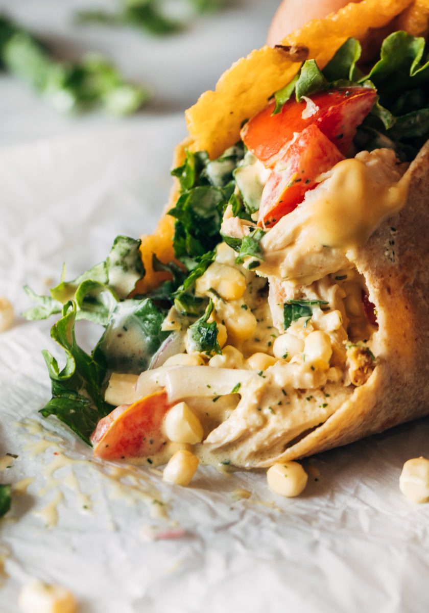 Juicy close up of the chicken wrap with toppings falling out.