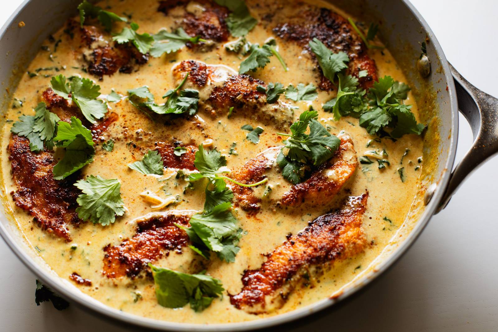 Cooked chicken in a pan with coconut sauce.